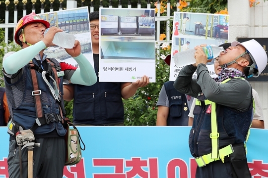 7월 24일 오전 서울 종로구 정부서울청사 앞에서 열린 '건설현장 폭염 안전규칙 이행 촉구 기자회견'에 참석한 송영철(왼쪽) 건설노조 전북건설지부 분회장, 우영인 건설노조 서울건설지부 부지부장이 물을 마시는 퍼포먼스를 하고 있다. 2018.07.24. 20hwan@newsis.com